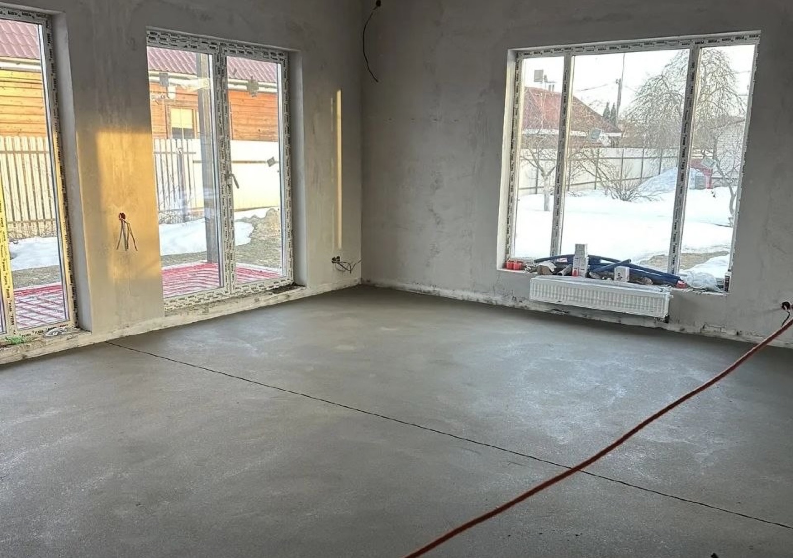 Готовая полусухая стяжка пола в гостиной частного дома с панорамными окнами — пример выполненного объекта в Московской области, иллюстрация к статье о стоимости стяжки пола в 2026 году