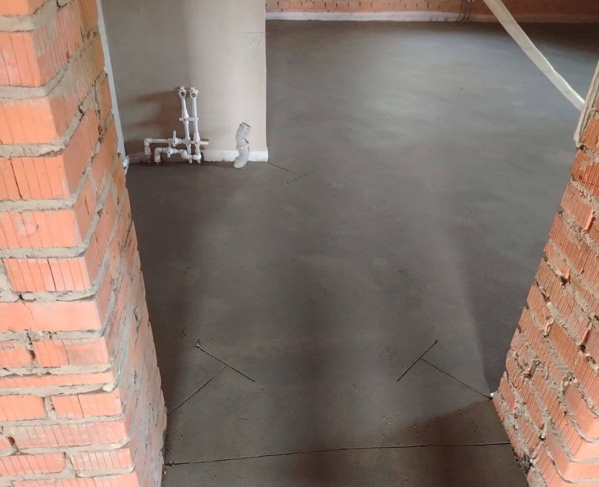 Полусухая стяжка в частном доме 90 м² в Кузнецово — комната с кирпичными стенами, разводкой водоснабжения и компенсационными швами