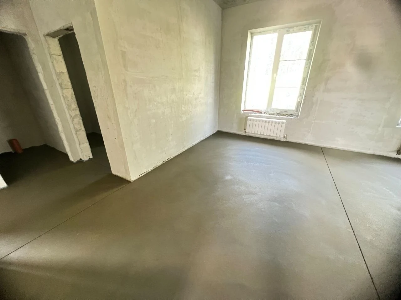 Полусухая стяжка в частном доме 130 м² в Старотеряево - комната с окном, радиатором и проемом в соседнее помещение