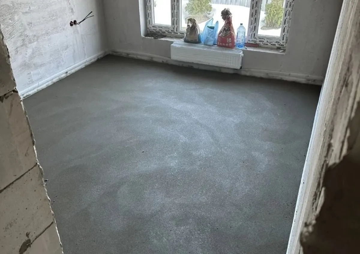 Полусухая стяжка в частном доме 150 м² в деревне Стулово - жилая комната с газобетонными стенами и свежей стяжкой
