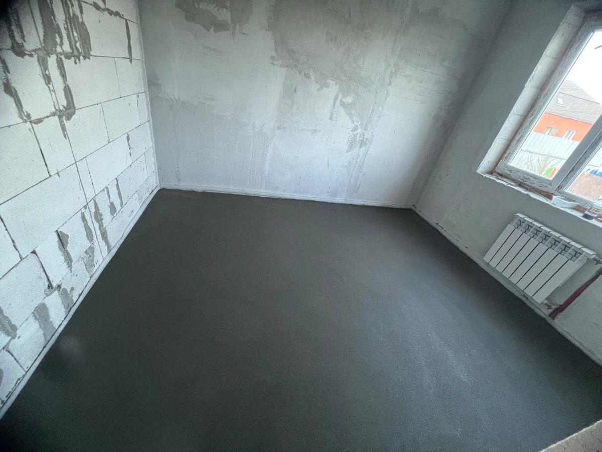 Полусухая стяжка в комнате дома 137,9 м² в поселке Всеволодово — ровный слой у радиатора под окном