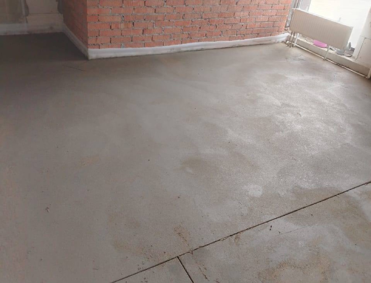 Полусухая стяжка в магазине 110 м² в Троицке — угол с кирпичной стеной и радиатором