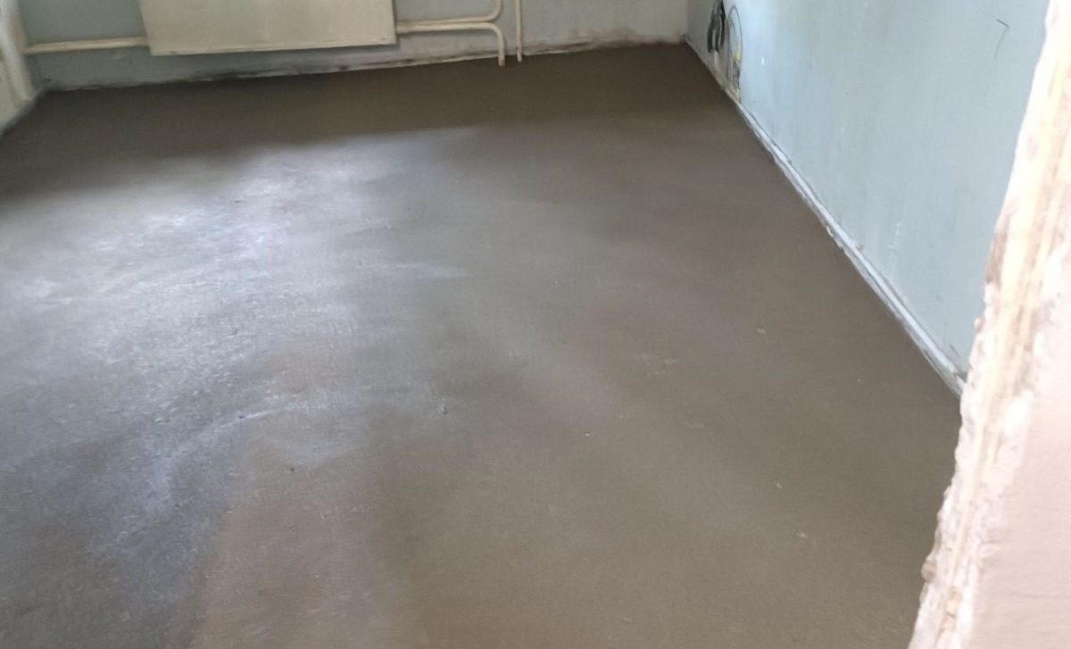Свежая полусухая стяжка в комнате квартиры 48 м² на улице Ситникова в Балашихе — ровная поверхность после полуручной заливки