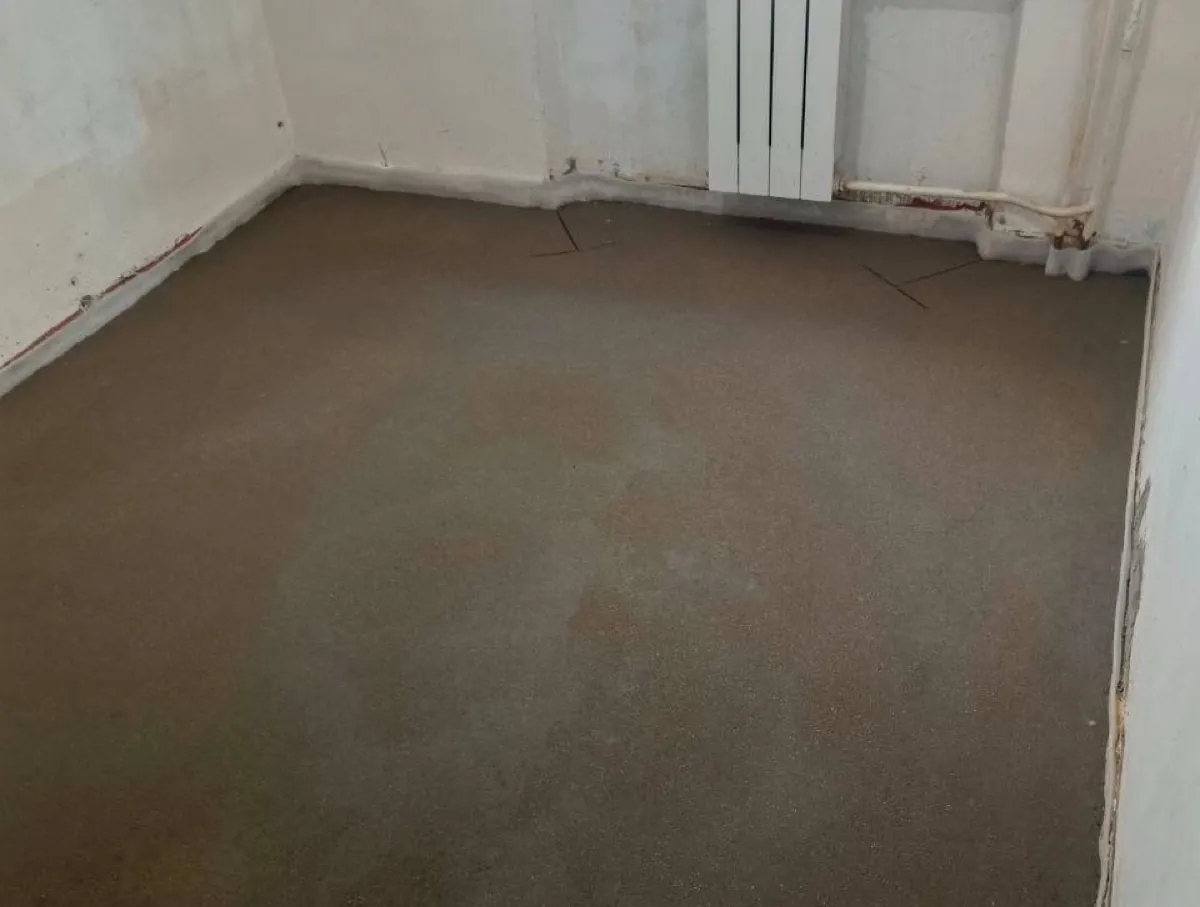 Свежая полусухая стяжка в комнате квартиры 45 м² на Байкальской улице в Москве - ровная поверхность и компенсационный шов