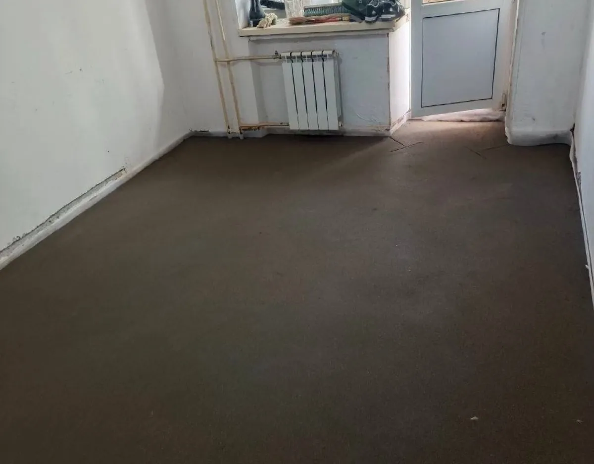 Полусухая стяжка пола 45 м² в квартире на Байкальской улице в Москве - ровная поверхность в комнате с радиатором под окном
