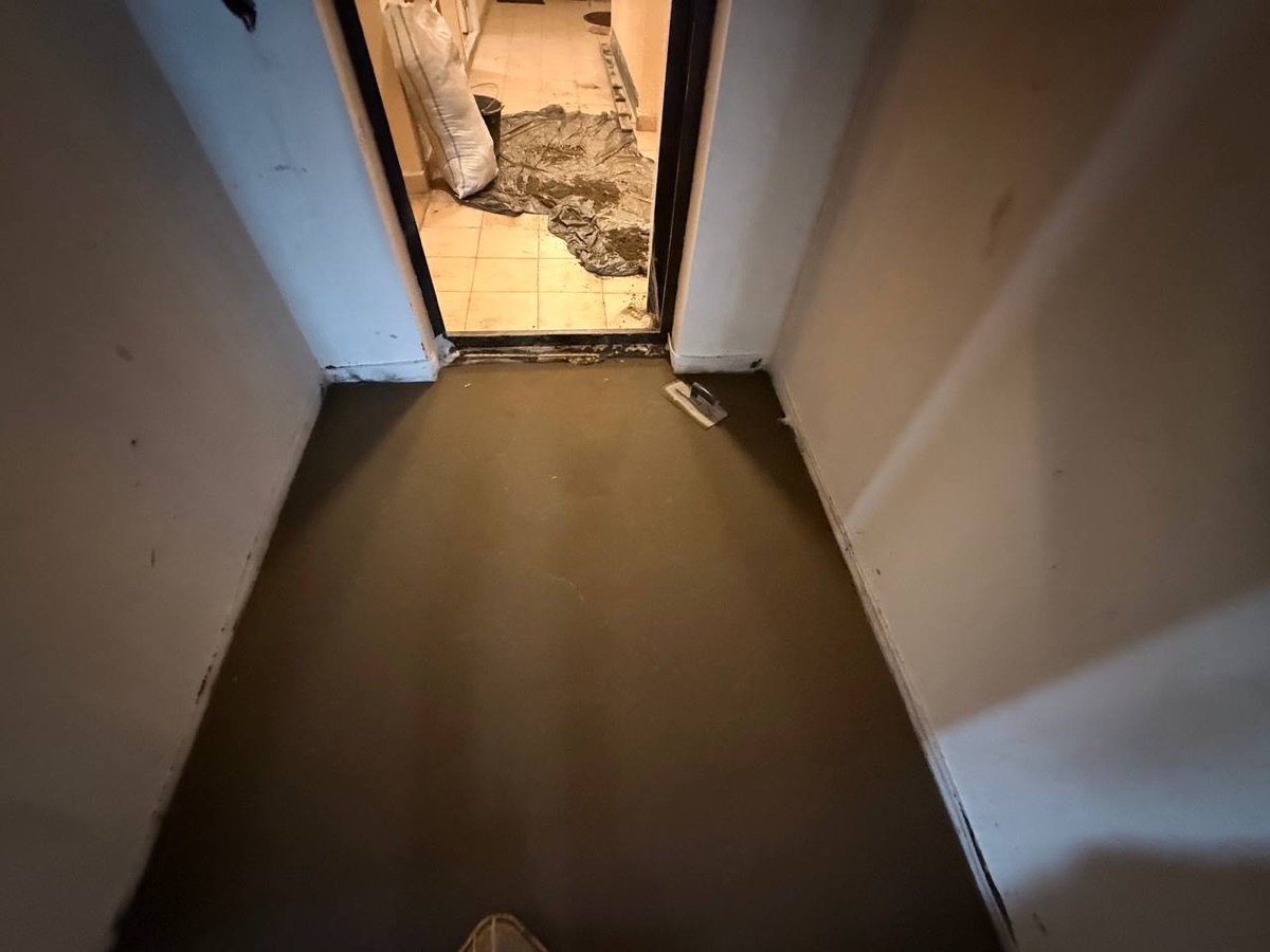 Полусухая стяжка в квартире 77,2 м² в Москве — свежий слой в прихожей у входа
