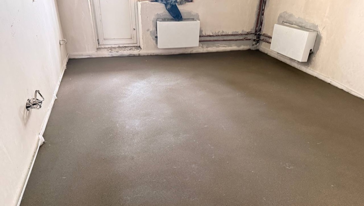 Полусухая стяжка пола 77,2 м² в квартире на улице Герасима Курина в Москве — ровная поверхность в комнате с радиаторами