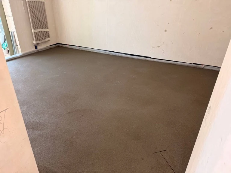 Полусухая стяжка пола 34 м² в квартире в квартале 160 в Коммунарке - ровная поверхность в комнате с радиатором у окна