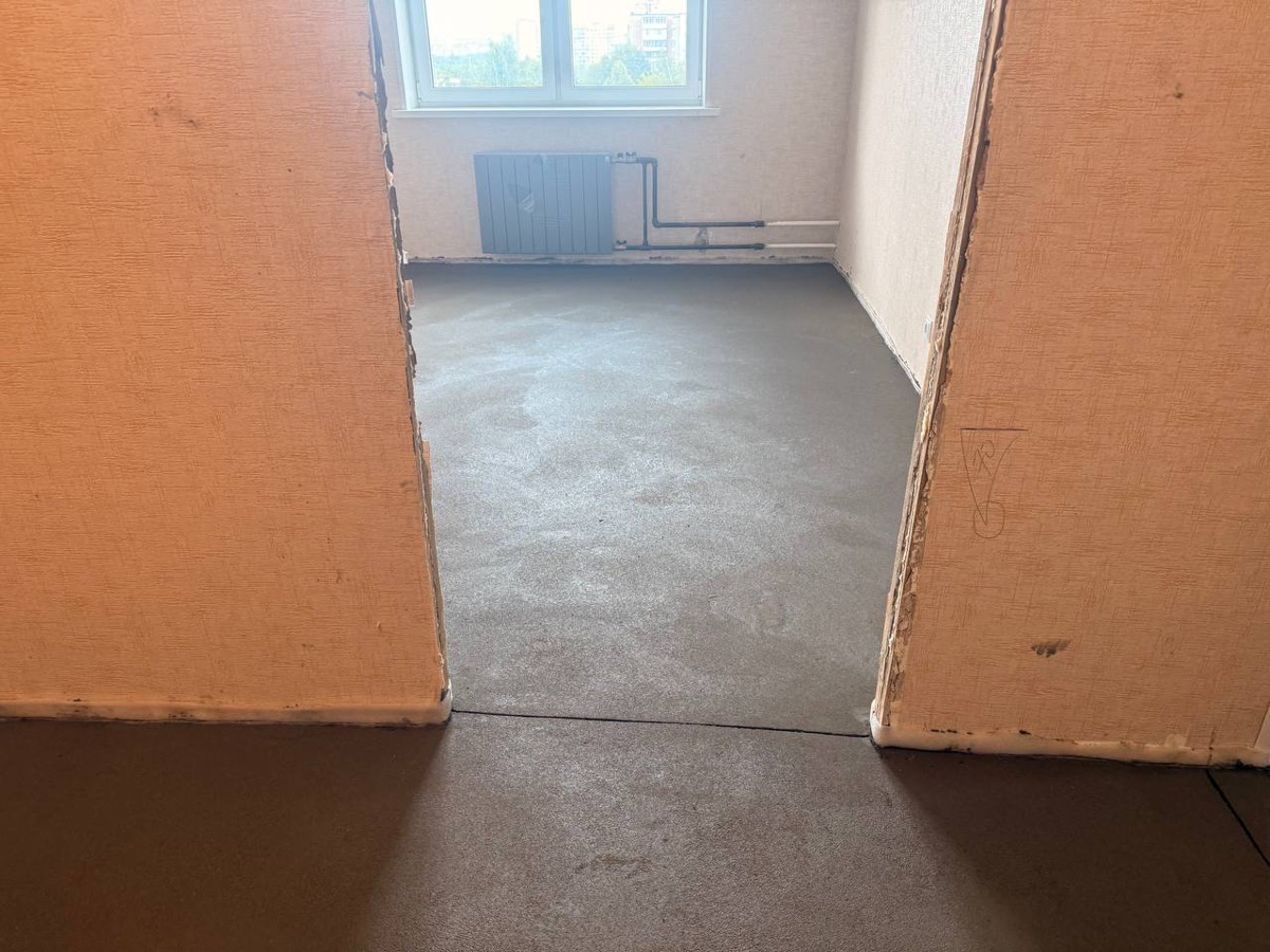 Полусухая стяжка в квартире 50 м² в Москве — комната с окном и радиатором, ровное основание