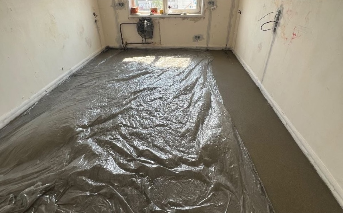 Уход за полусухой стяжкой в квартире 54 м² в Видном — свежий слой укрыт пленкой для равномерного набора прочности