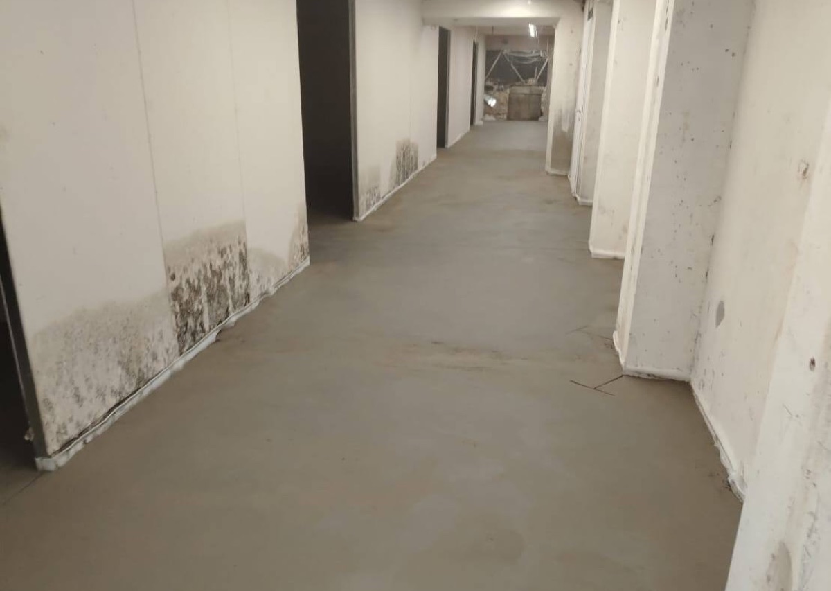 Полусухая стяжка пола 253 м² на цокольном этаже торгового центра на Дубнинской улице в Москве — ровный пол в длинном коридоре с колоннами